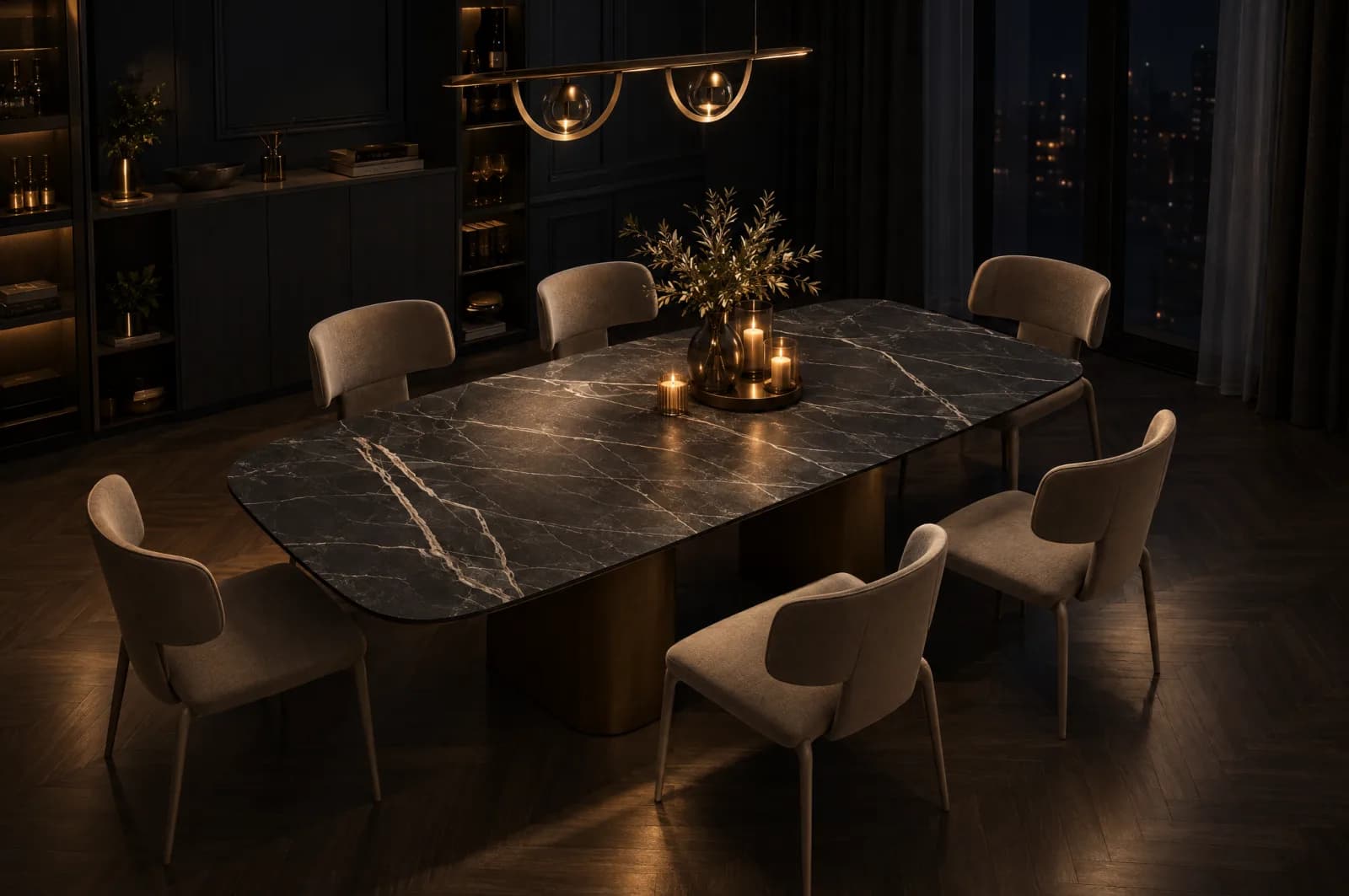 Dark panelled dining room at night with a low linear pendant and candles lighting a Calacatta Black porcelain table, its white veining glowing against the black top, with taupe upholstered chairs and the room falling into shadow